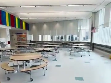Wide cafeteria view showing tables and presentation space.