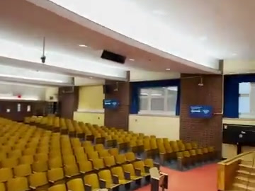 Wide auditorium view showing seating and installed wall displays.